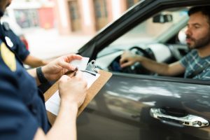 Police officer writing traffic ticket for driver during roadside stop