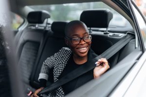 Smiling woman fastening her seat belt in the backseat of a car