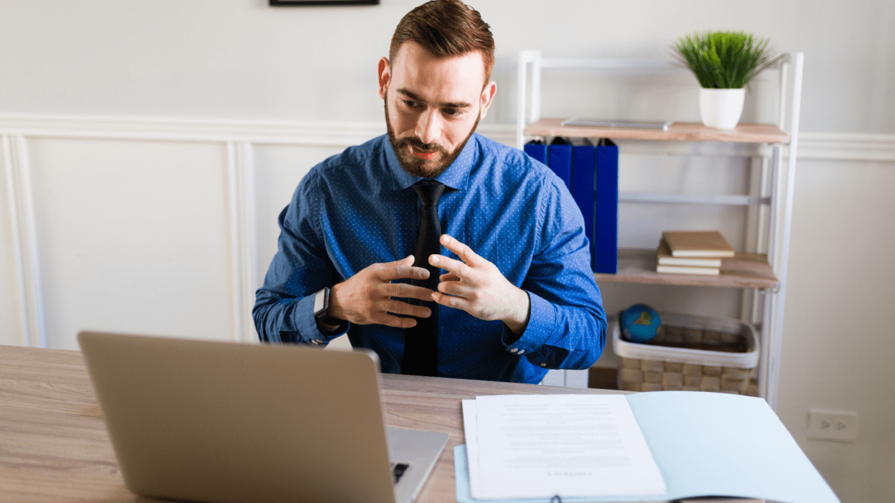 A lawyer in a blue shirt is consulting a client over a video call about a speeding ticket
