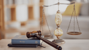 A gavel and a law book beside the scales of justice in a courtroom