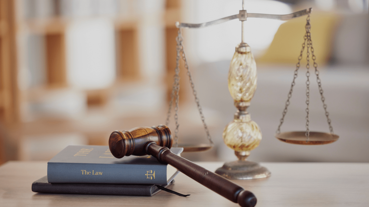 A gavel and a law book beside the scales of justice in a courtroom
