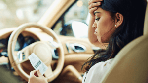 Frustrated driver holding a speeding ticket while sitting in car