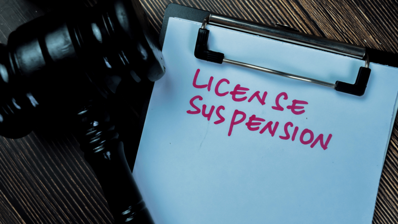 Clipboard labeled “License Suspension” beside a gavel — suspended license attorney concept