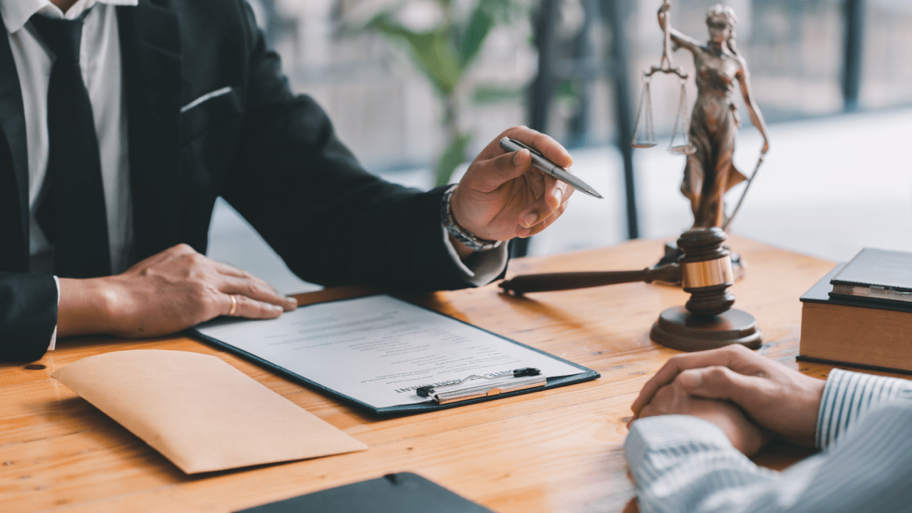 Lawyer consulting client at office desk with legal documents and gavel