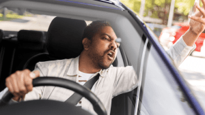 Aggressive driver displaying road rage behavior while driving, illustrating can you sue for reckless driving situations