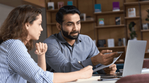 Couple consulting with lawyer on how to beat a speeding ticket, reviewing legal documents at office desk