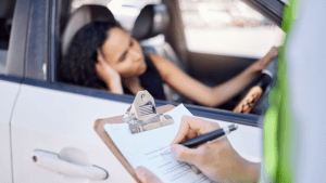 Police officer writing traffic ticket while driver waits showing how long do traffic violations stay on record process begins