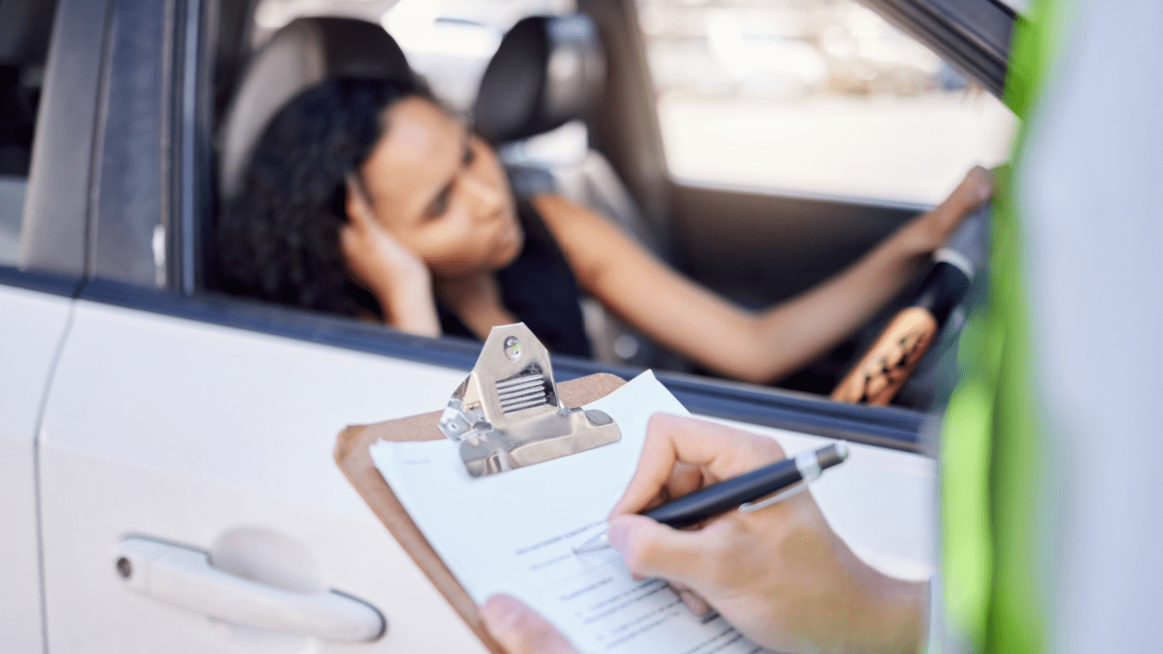 Police officer writing traffic ticket while driver waits showing how long do traffic violations stay on record process begins