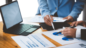 Legal professionals analyzing case documents and charts at wooden desk with laptop, illustrating what is a traffic lawyer and their analytical work on traffic violation cases