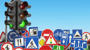 Traffic light and road signs showing why do traffic laws exist to regulate driver behavior