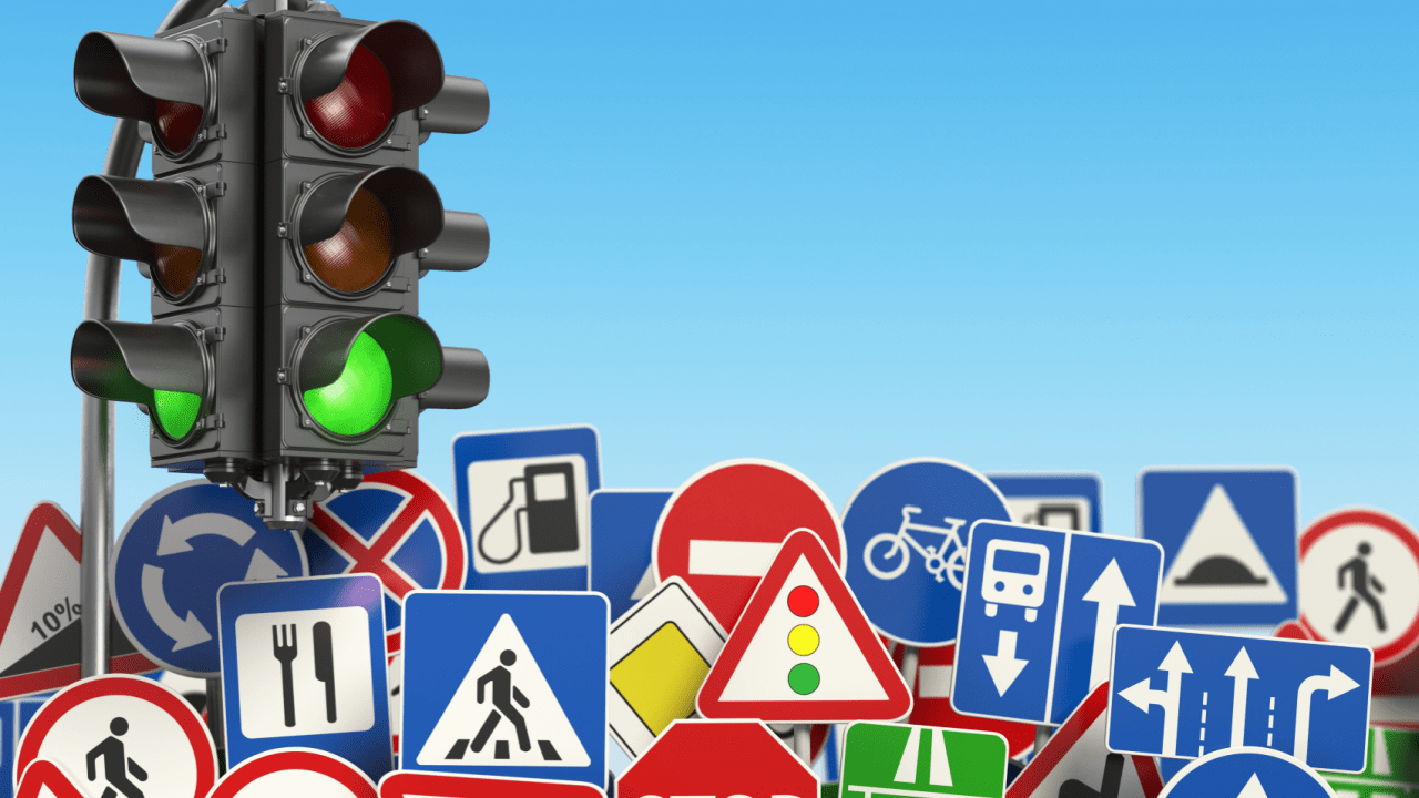Traffic light and road signs showing why do traffic laws exist to regulate driver behavior