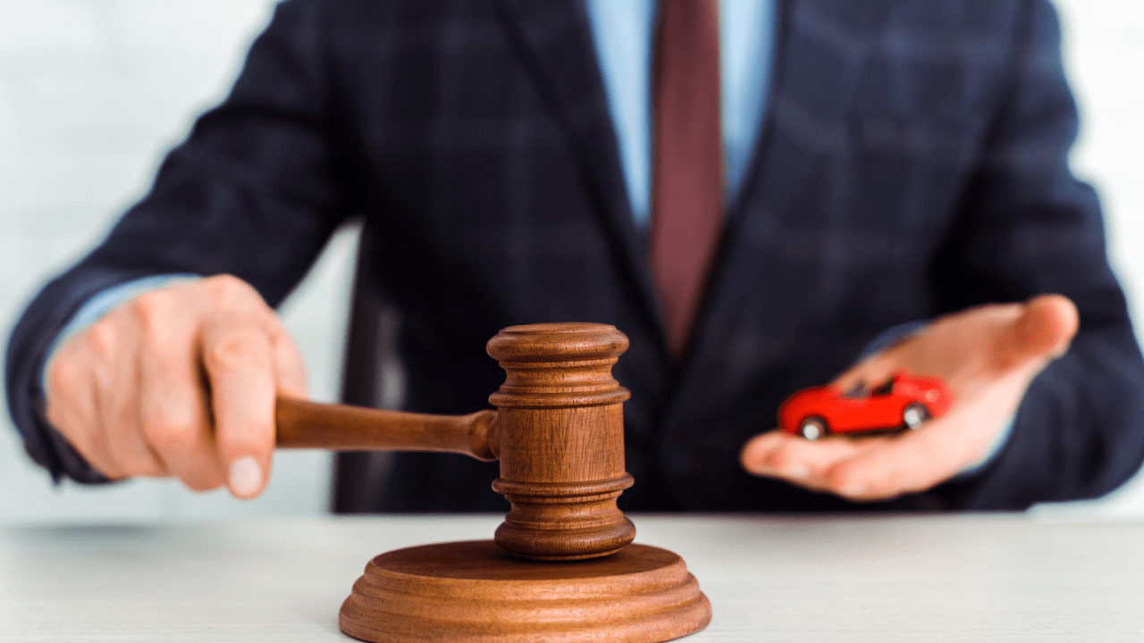 Legal professional with gavel and red toy car representing enforcement and authority of traffic laws
