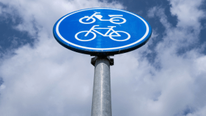 Blue traffic sign showing traffic laws for cyclists and bicycles on shared pathway against sky