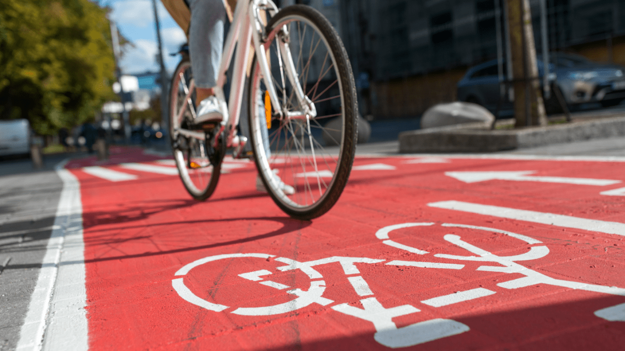 Cyclist riding bicycle on red bike lane showing do bicycles have to follow traffic laws concept