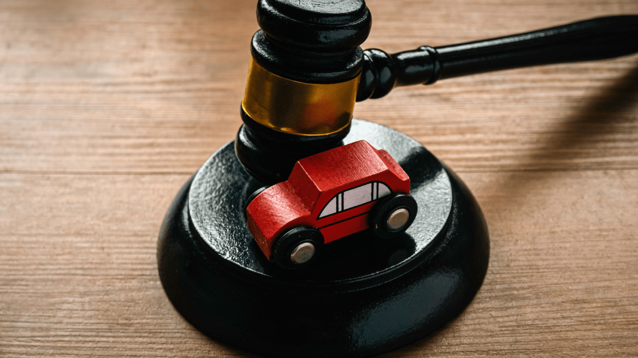 Wooden gavel and red toy car representing how can a traffic lawyer help with reckless driving cases