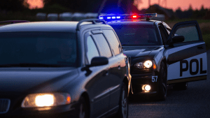 Police officer conducting traffic stop to enforce what are the basic traffic laws on highway at dusk