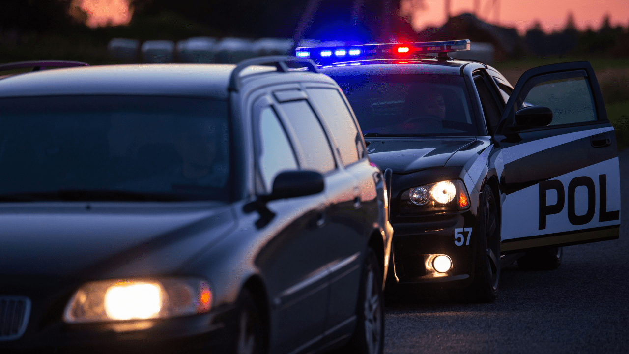 Police officer conducting traffic stop to enforce what are the basic traffic laws on highway at dusk