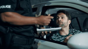 Driver facing police officer during traffic stop showing CDL ticket consequences