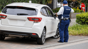 Police officer writing traffic ticket for white car driver deciding is it better to just pay a ticket or go to court