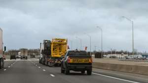 Company vehicle with oversize load sign driving on highway showing what happens if you get pulled over in a company vehicle