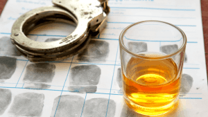 Which state has the harshest DUI laws concept showing handcuffs whiskey glass and fingerprint card on legal documents