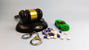 First offense DUI under state law consequences showing gavel handcuffs pills and toy car representing jail time exposure