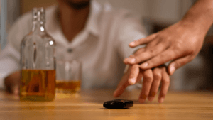 Person refusing alcohol with car keys on table illustrating states with zero alcohol tolerance laws for underage drivers