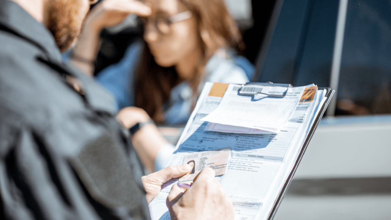 A police officer reviewing a driver's license and traffic violation documents during a careless driving stop in New Jersey