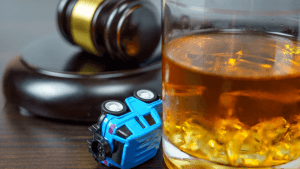 Gavel, toy car, and alcoholic drink illustrating what is the one two five drinking rule under state DUI guidance