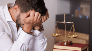 Will I go to jail for careless driving — man in handcuffs sitting before scales of justice